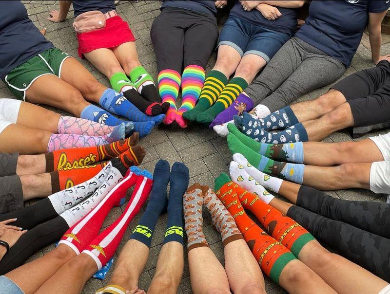 Group of people showing colorful striped socks in a circle for the Show Your Stripes campaign