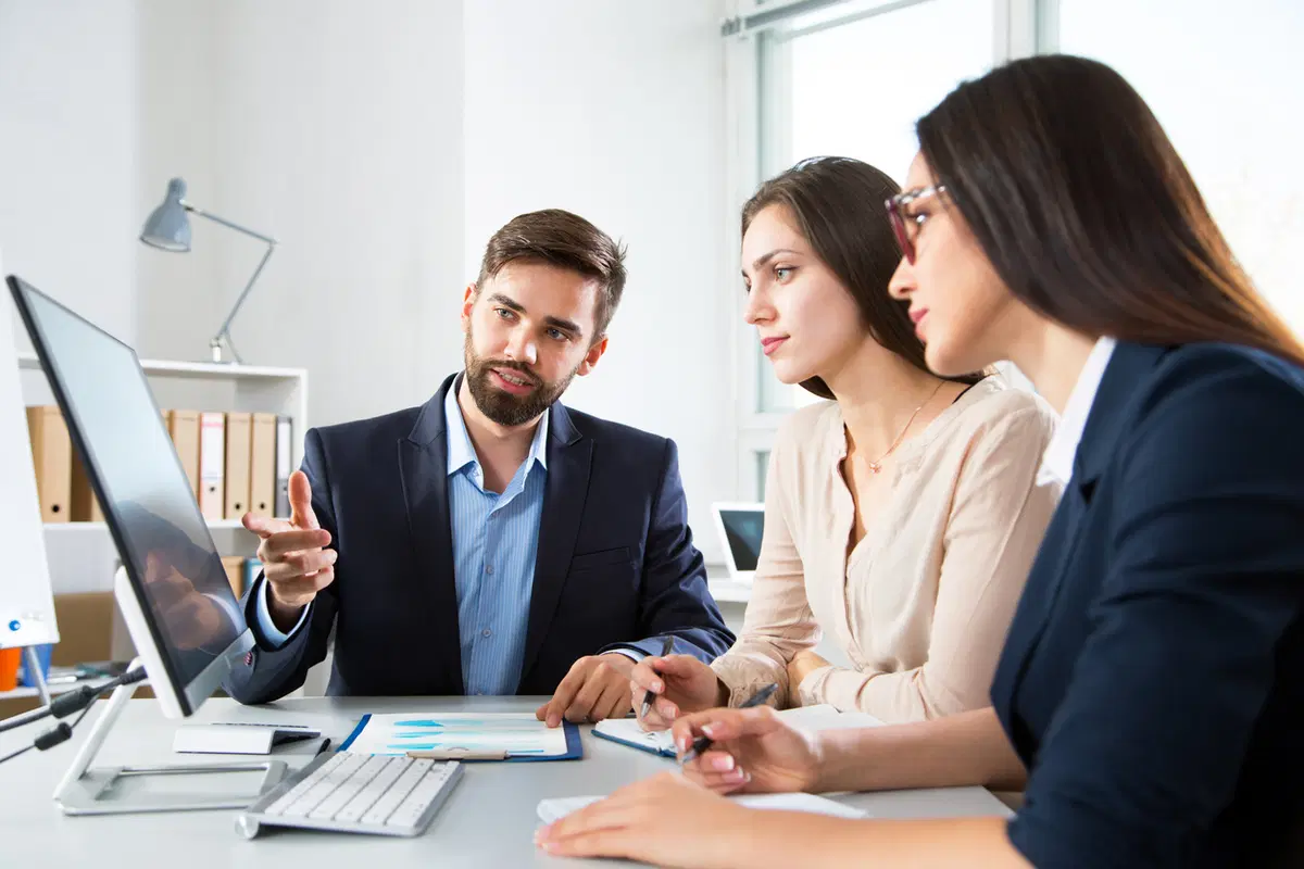 Team of three reviewing computer screen — group benefits enrollment training session