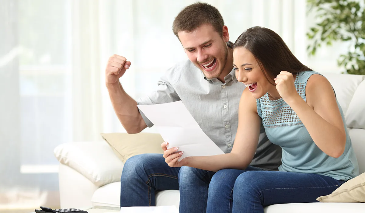 A couple smiling and reviewing a benefits document together at home