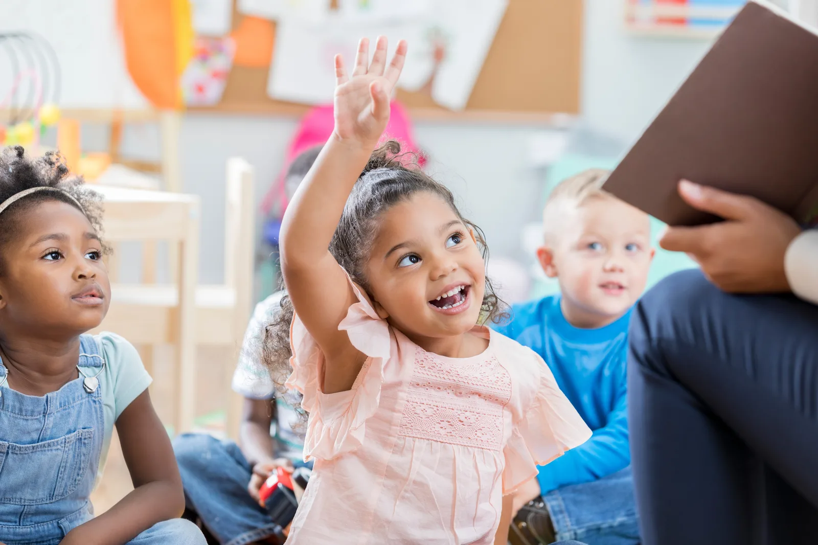 Young child raising her hand in a classroom, representing this week's dependent care FSA and private school tuition question